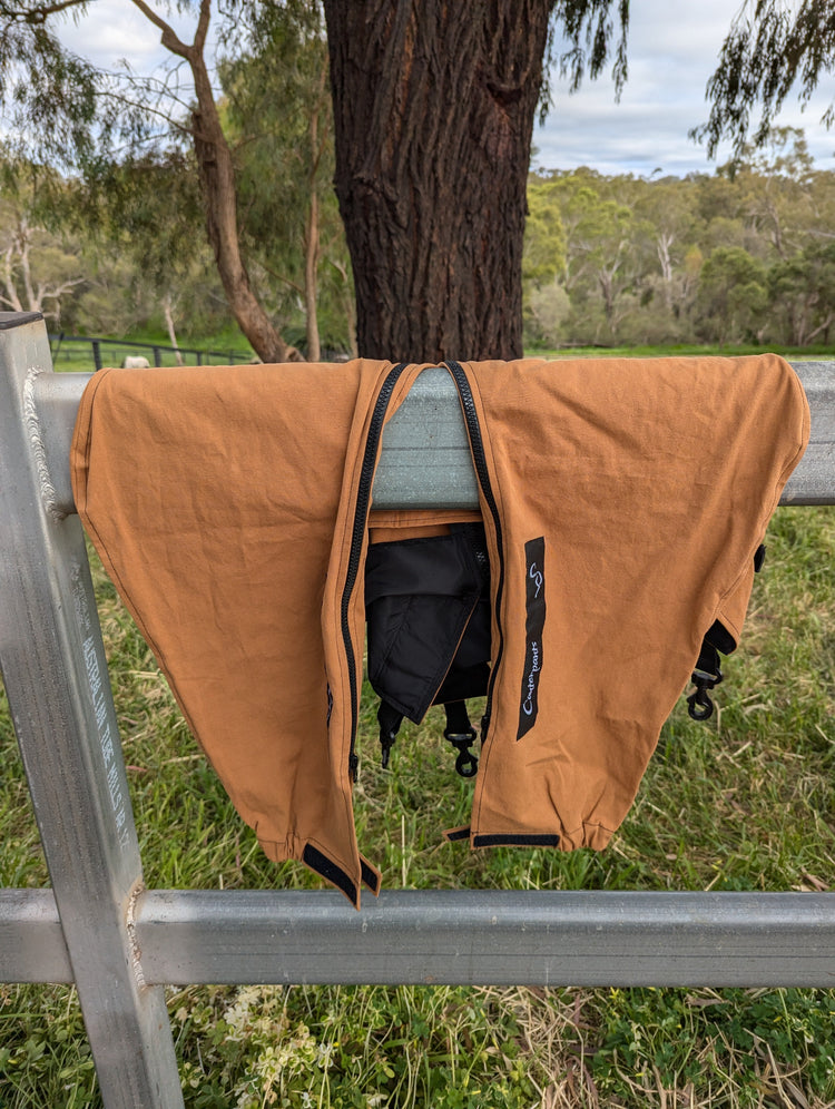 Pair of desert coloured horse pants hanging over a railing