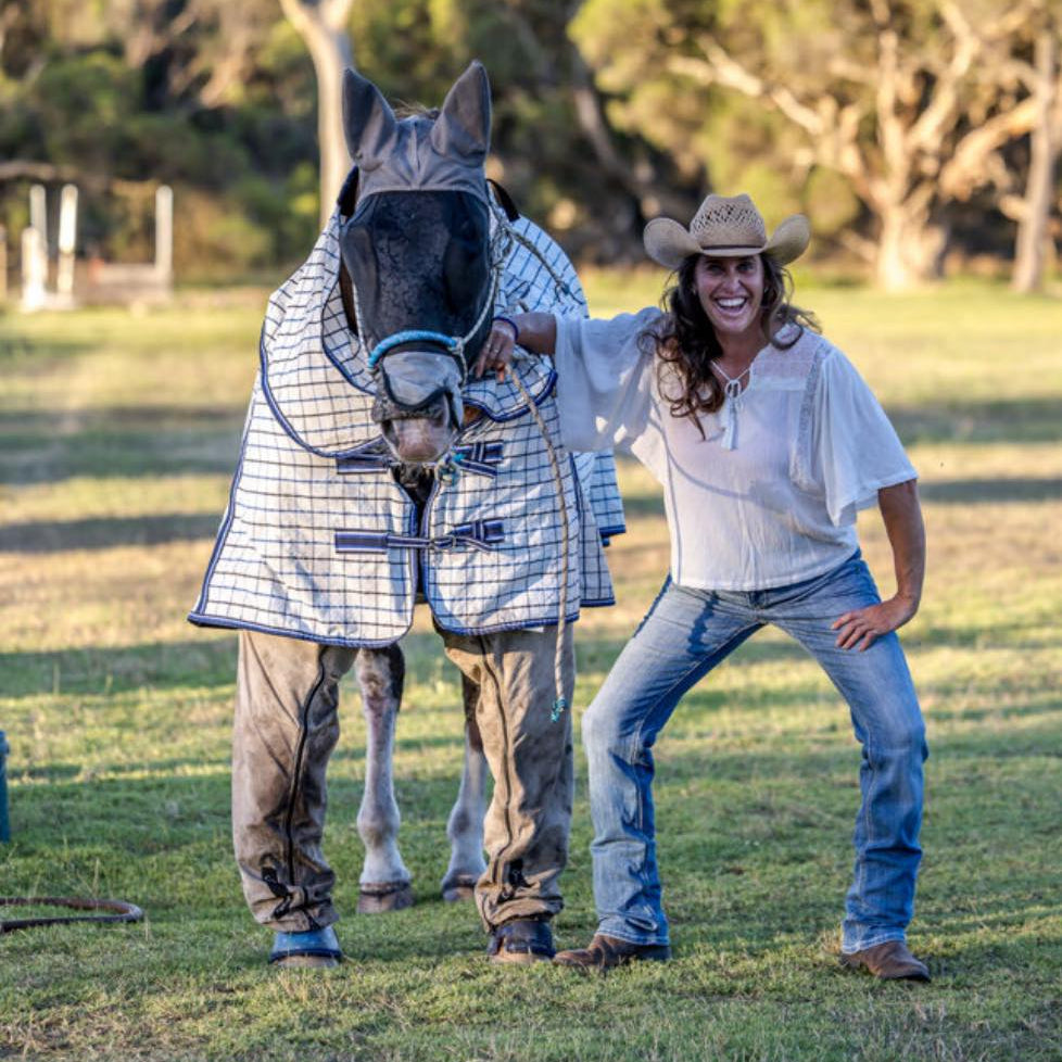 Horse wearing a rug, pants and a fly veil to protect from insect bites next to owner mimicing horse's stance and lauging