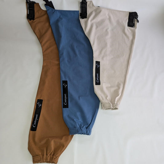 Three front Canterpants legs (large desert brown, medium ocean blue and small beach beige) laid flat on a white background